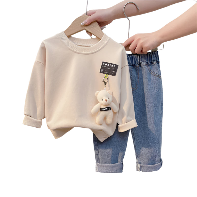 Cute toddler boy clothes with bear plush toy on cream sweatshirt and blue rolled-up jeans set