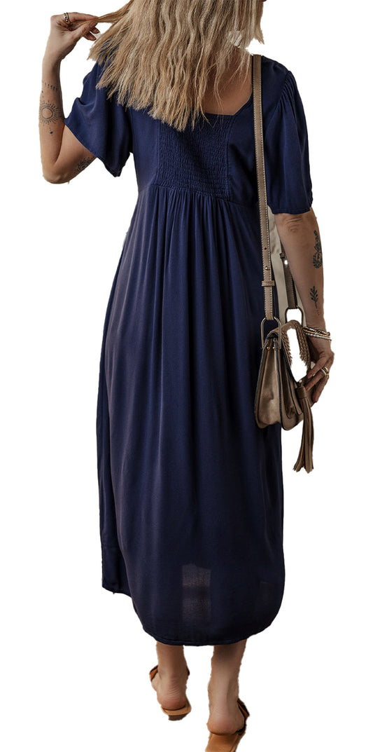 Back view of woman wearing navy blue midi dress with smocked bodice short sleeves and tan crossbody bag