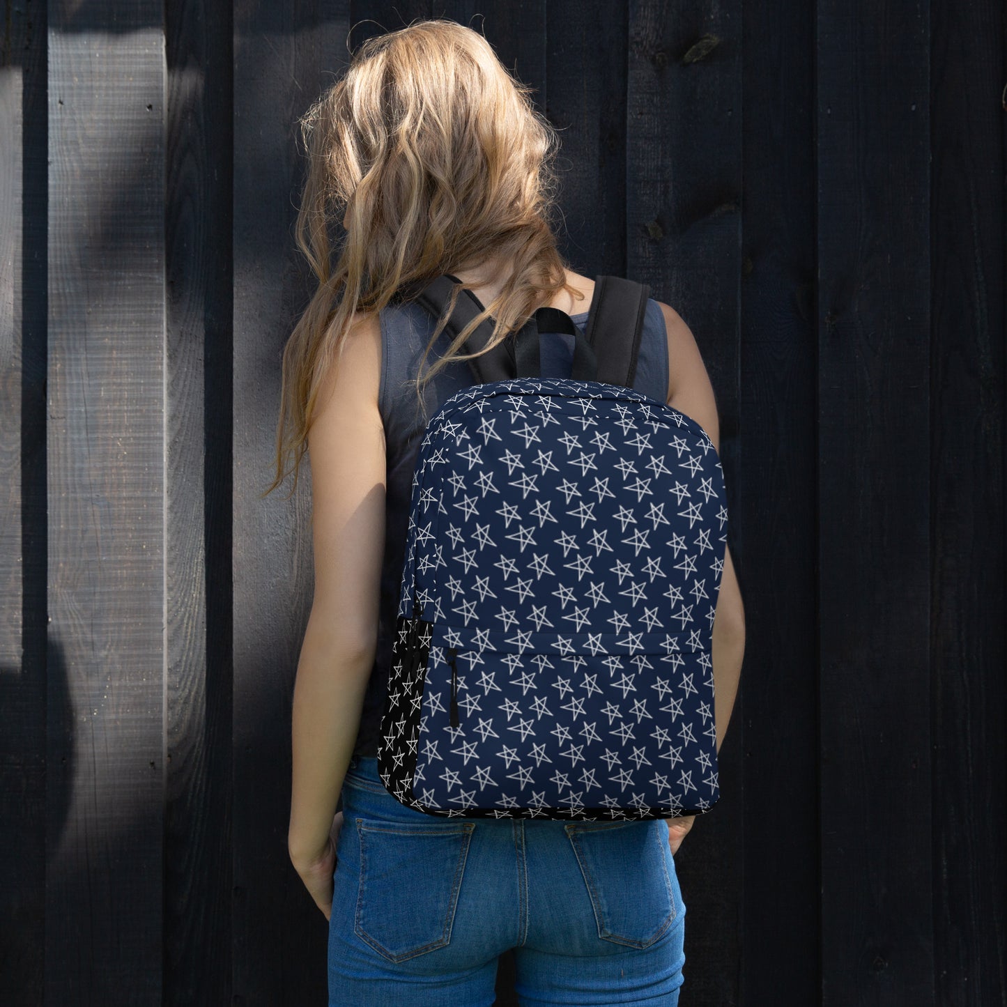 Woman wearing a navy LuckeLadybug star pattern backpack with white stars against a dark wooden background