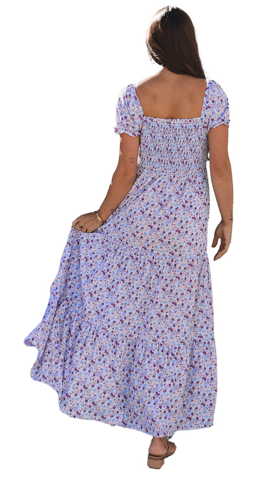 Model wearing purple floral maxi dress with smocked square back, puff sleeves and tiered flowing skirt