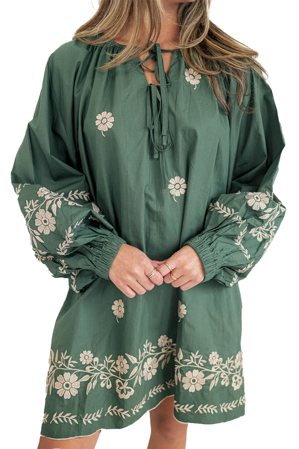 Model wearing mist green boho floral dress with long puff sleeves embroidered hem and tie neckline