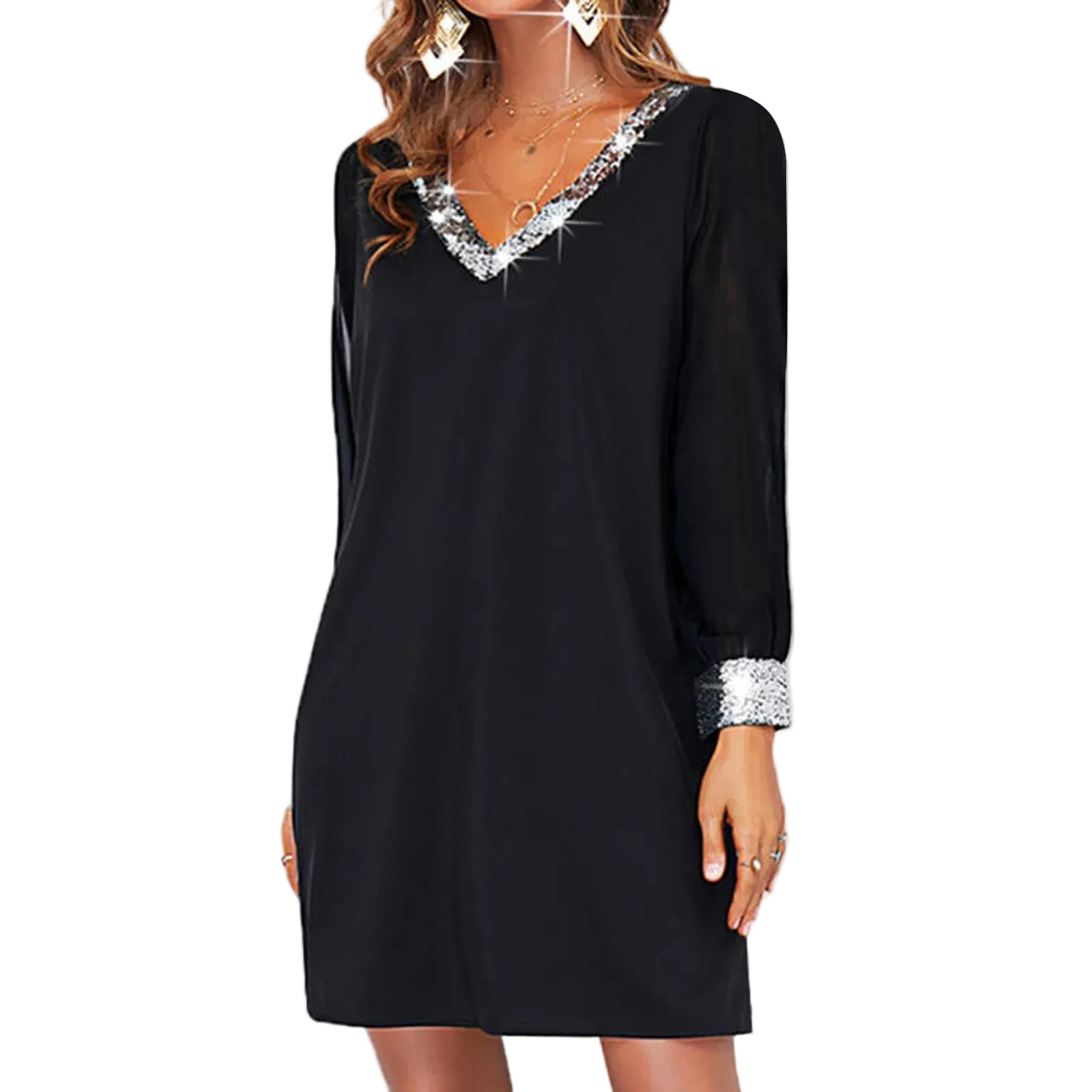 A woman wearing a black long-sleeve mini dress with a sparkling silver embellished V-neckline and matching silver cuff details, standing against a white paneled wall.