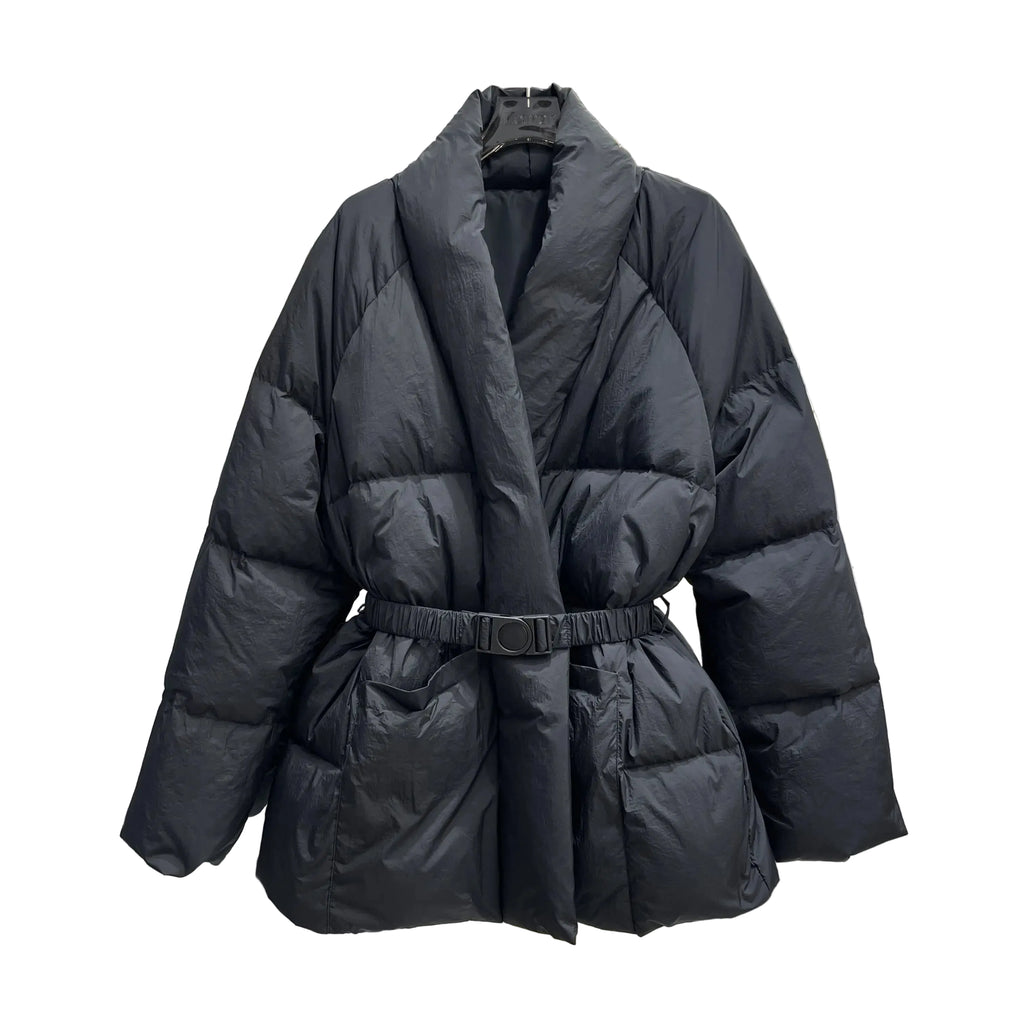 A black puffer jacket with a shawl collar and a matching elastic belt, displayed on a hanger in a clothing store.