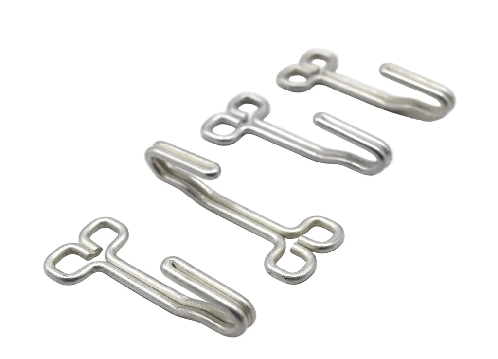 Four small silver metal hook-like hardware pieces arranged diagonally on a plain white background.
