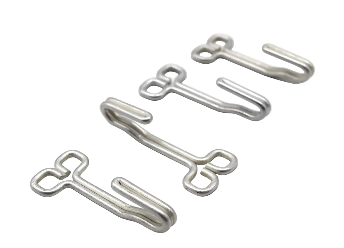 Four small silver metal hook-like hardware pieces arranged diagonally on a plain white background.