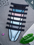 Six men's thong underwear briefs stacked vertically on a gray fabric background, featuring different color panels (black, navy, blue, pink, white, light blue, gray) with black trim. A green leaf, a small pink block, and a white grid-patterned paper are placed as props.