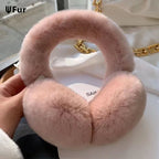 Pink fluffy ear warmers held by a hand with a blurred background