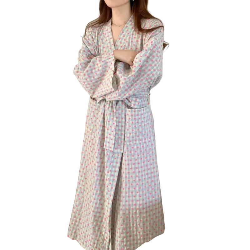 Woman wearing a long, patterned robe in a bedroom setting.