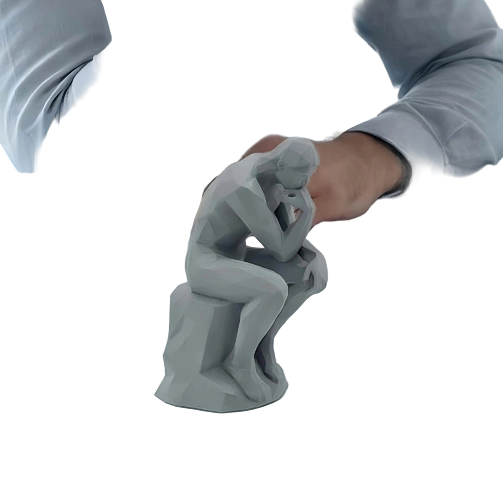 Gray 'Thinker' sculpture on a desk with a person in a gray shirt.
