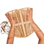A sheer nude-beige corset-style waist trainer with vertical boning and an elastic waistband, being held up by two visible arms against a plain light background.
