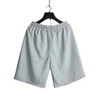 Light gray heathered sweatshorts with an elastic waistband hanging on a black hanger in an indoor setting.