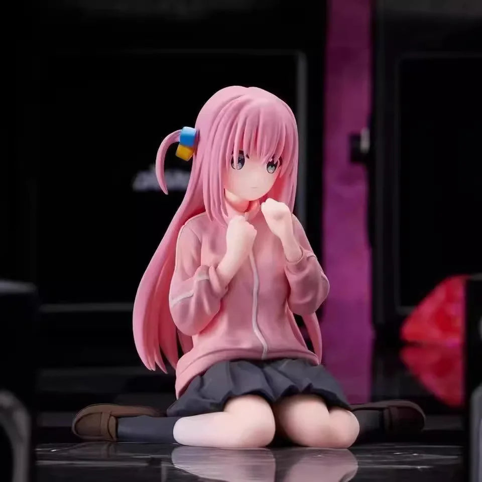 Anime figure of a girl with pink hair in a hoodie and skirt, sitting on the floor thoughtfully