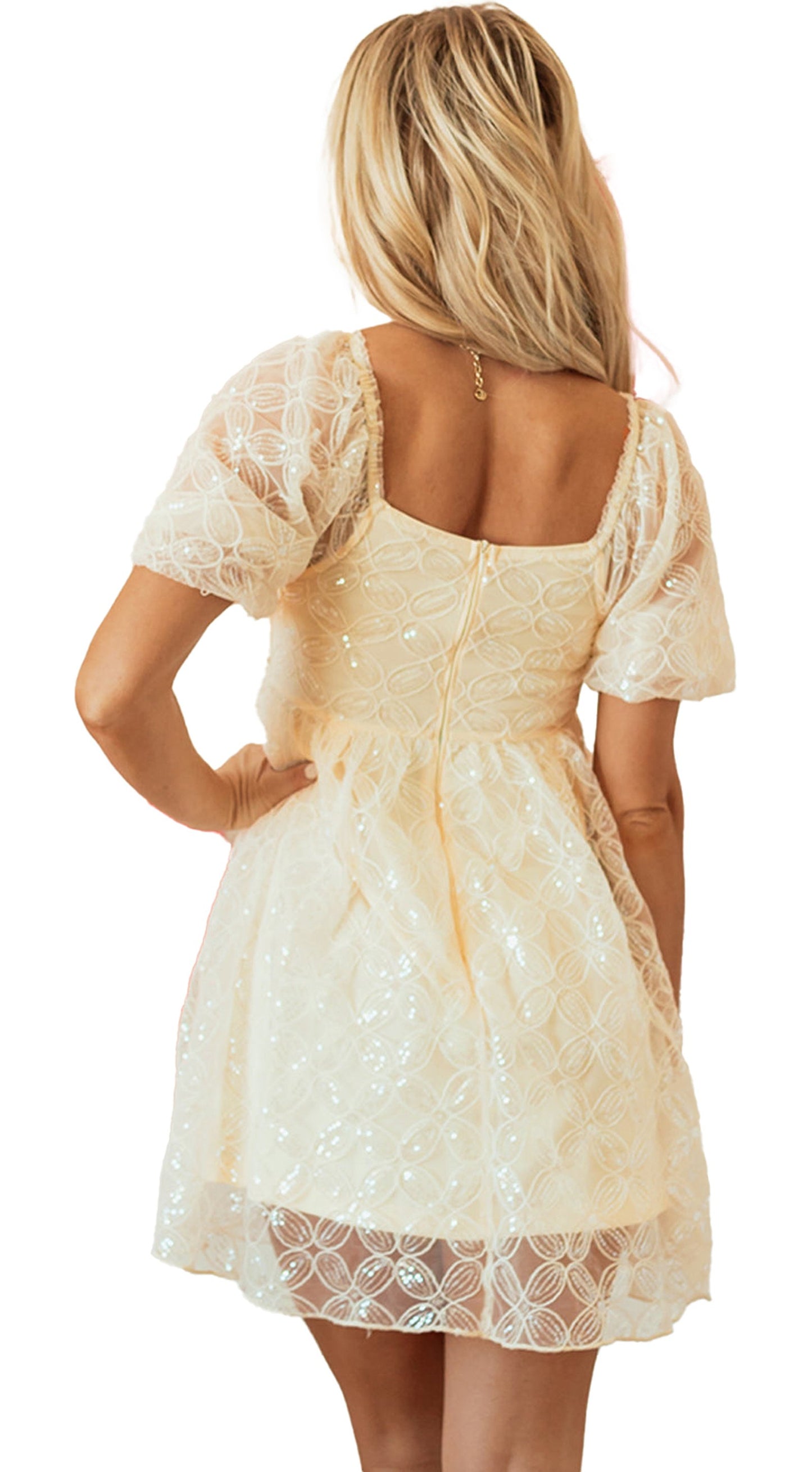 Back view of an apricot sequin lace dress with puff sleeves against a backdrop of heart-shaped balloons