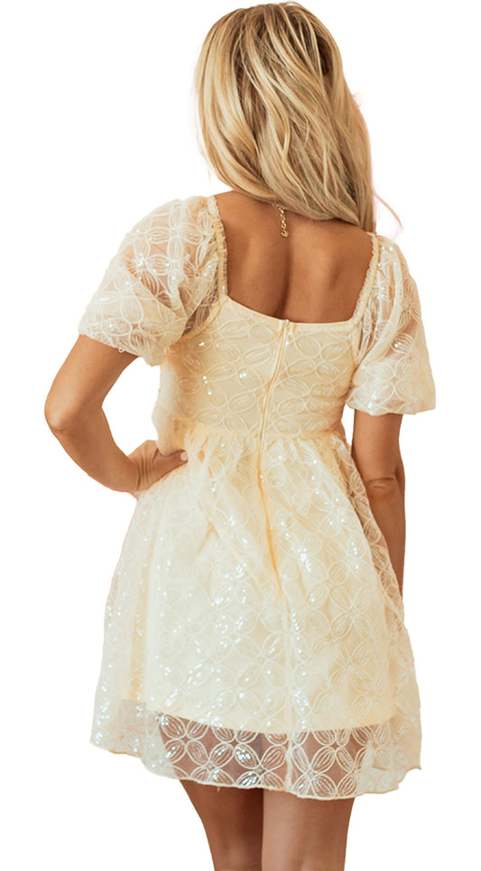 Back view of an apricot sequin lace dress with puff sleeves against a backdrop of heart-shaped balloons