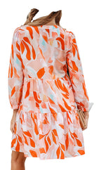 Woman wearing LuckeLadybug orange abstract print dress tiered mini with long sleeves and sun hat back view