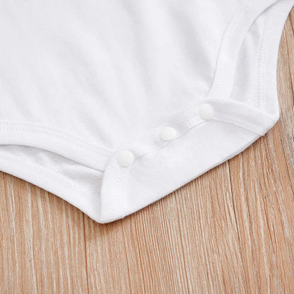 Close-up of a white baby Christmas outfit set featuring snap closures for easy dressing