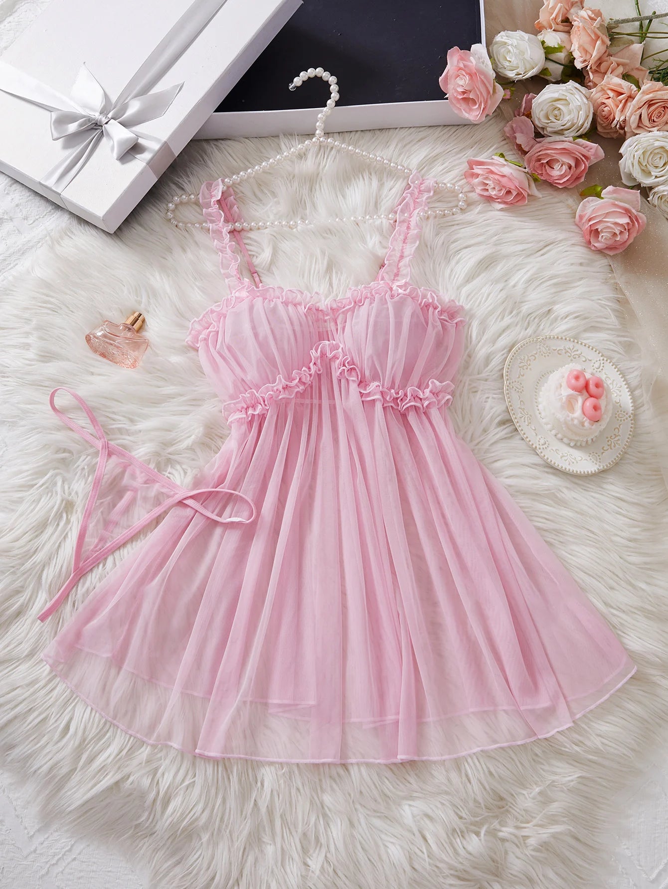 Pink LuckeLadybug LLC babydoll dress with lace trim and matching thong displayed on fluffy white background