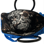 Blue crochet tote bag for crochet with a floral patterned interior and black handles