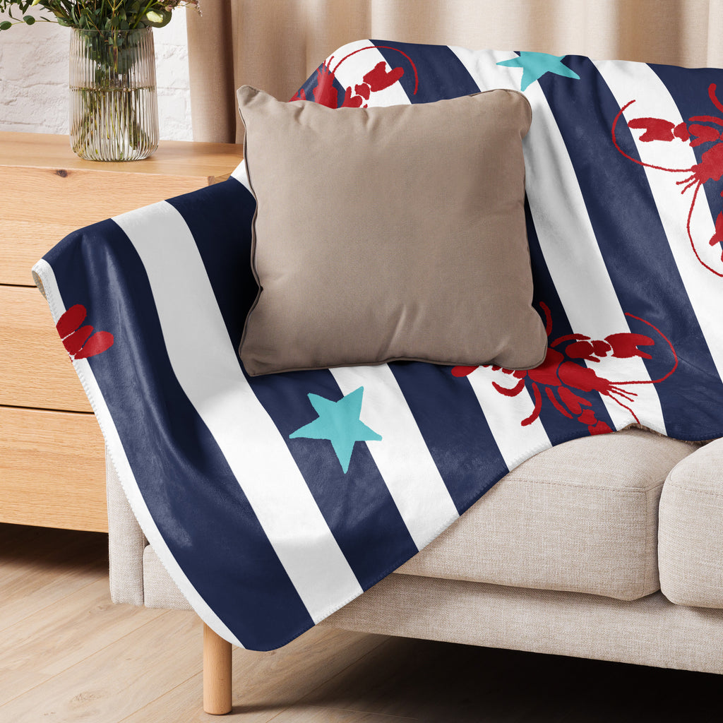 LuckeLAdybug beach theme sherpa blanket with navy stripes and red lobster pattern on a beige couch