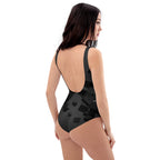 Model wearing LuckeLadybug black pattern one-piece swimsuit with subtle geometric square print and low scoop back
