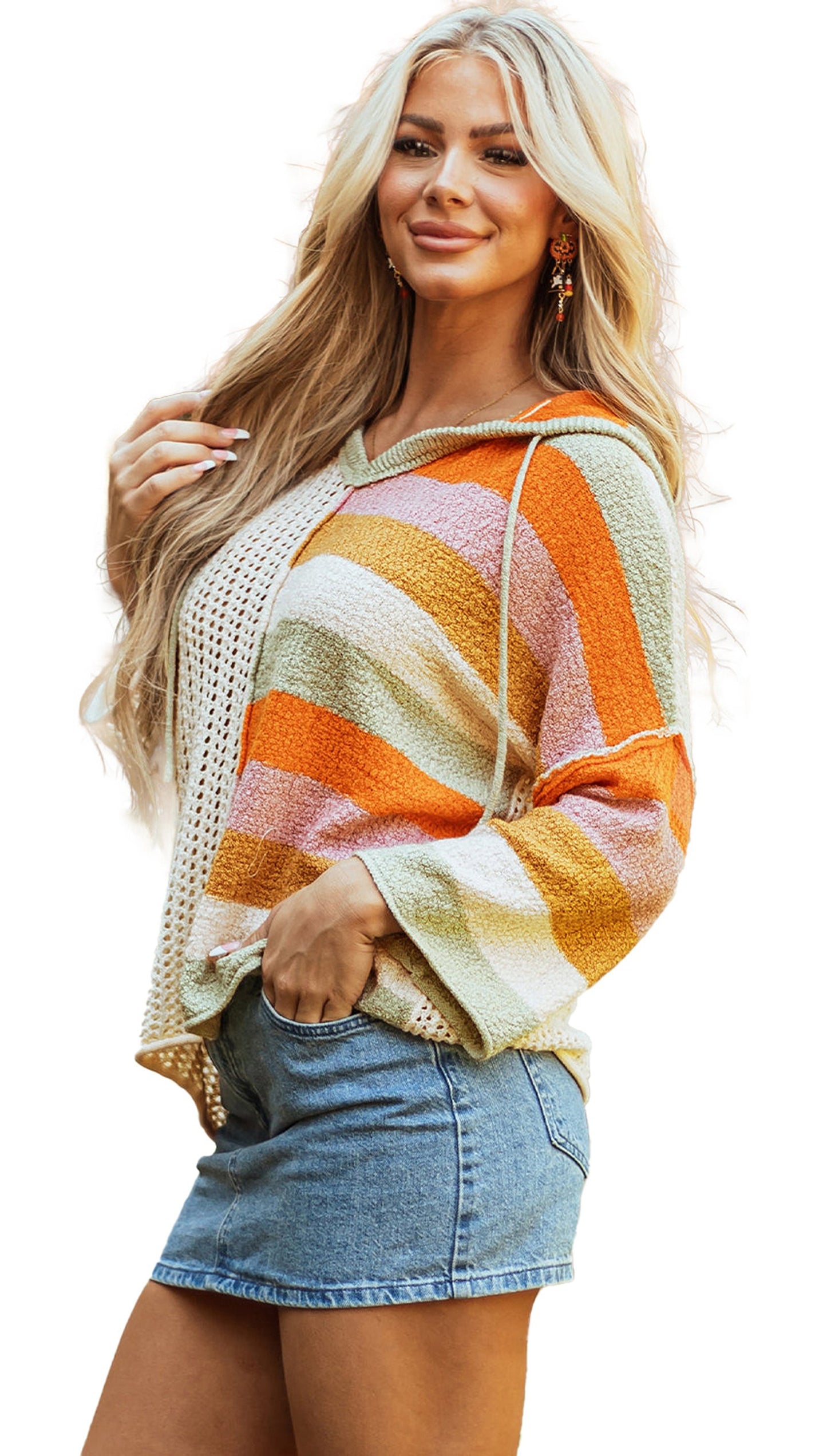 Woman wearing a beige oversized colorblock sweater with orange and green stripes, paired with a denim skirt