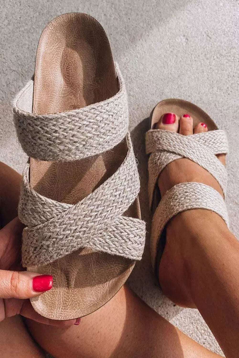 Beige woven slip-on sandals with crisscross straps from LuckeLadybug LLC shown on and held by a foot