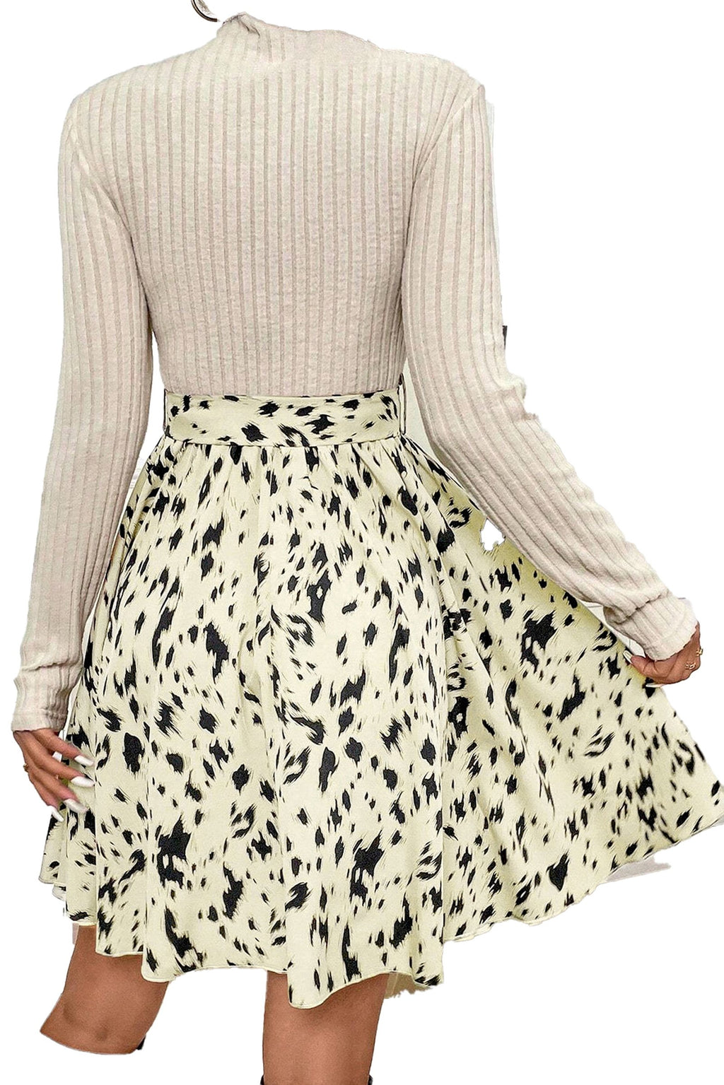 Back view of beige ribbed knit A-line dress with long sleeves and abstract black speckle skirt pattern