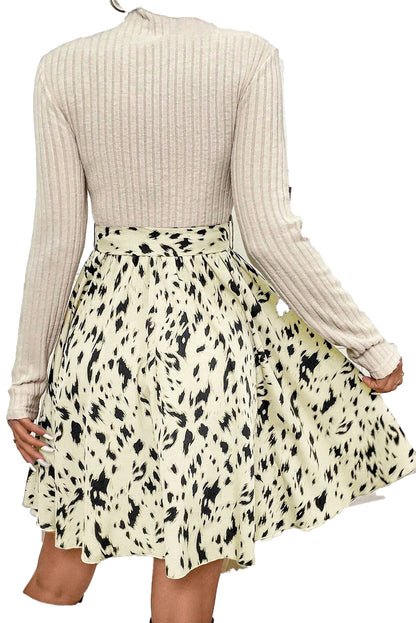 Back view of beige ribbed knit A-line dress with long sleeves and abstract black speckle skirt pattern