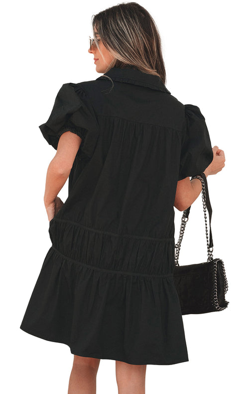 Model wearing black puff sleeve shirt dress back view with tiered mini skirt collar and chain shoulder bag
