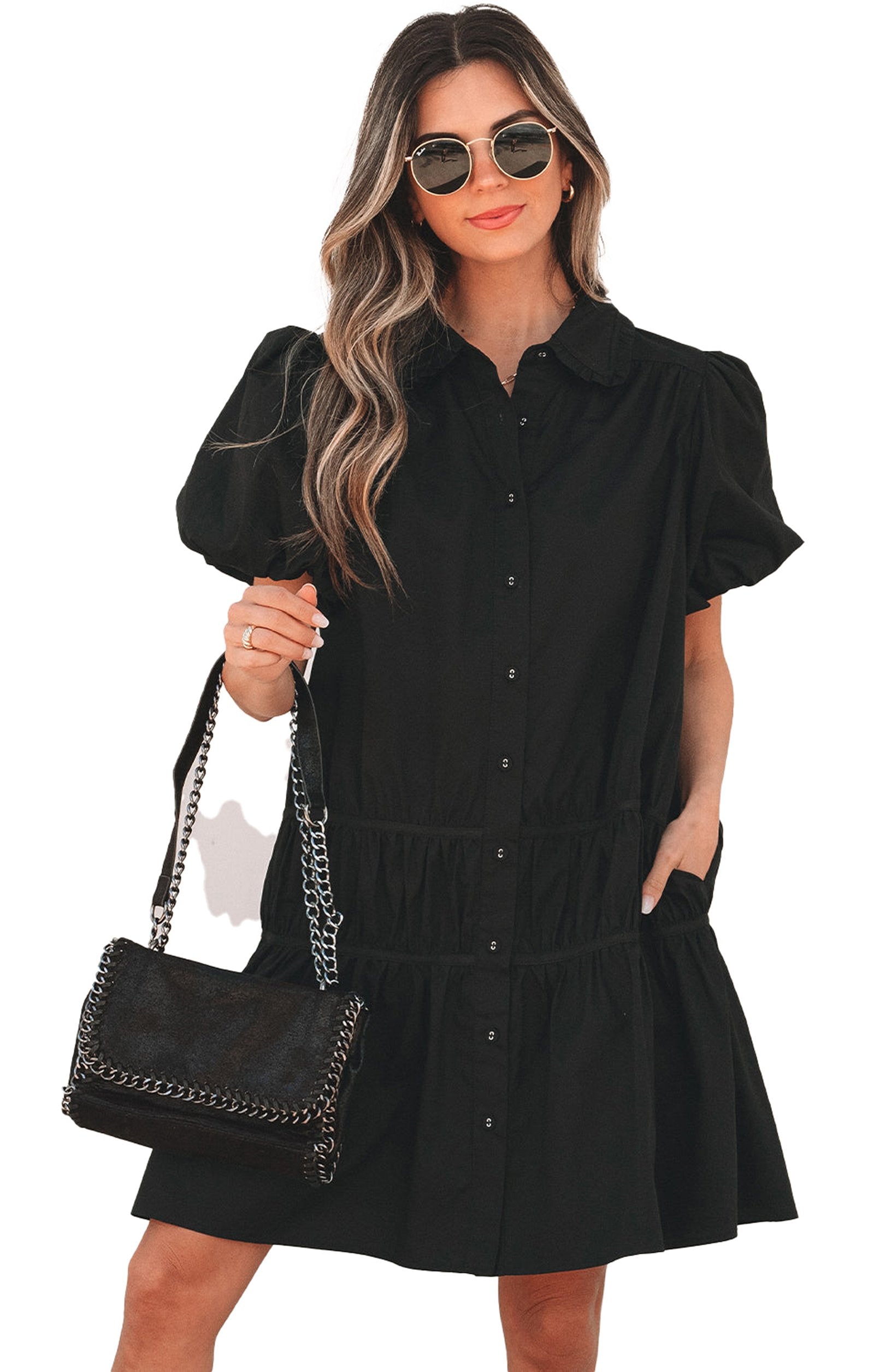 Model wearing black puff sleeve shirt dress with button front collar pockets and chain strap bag