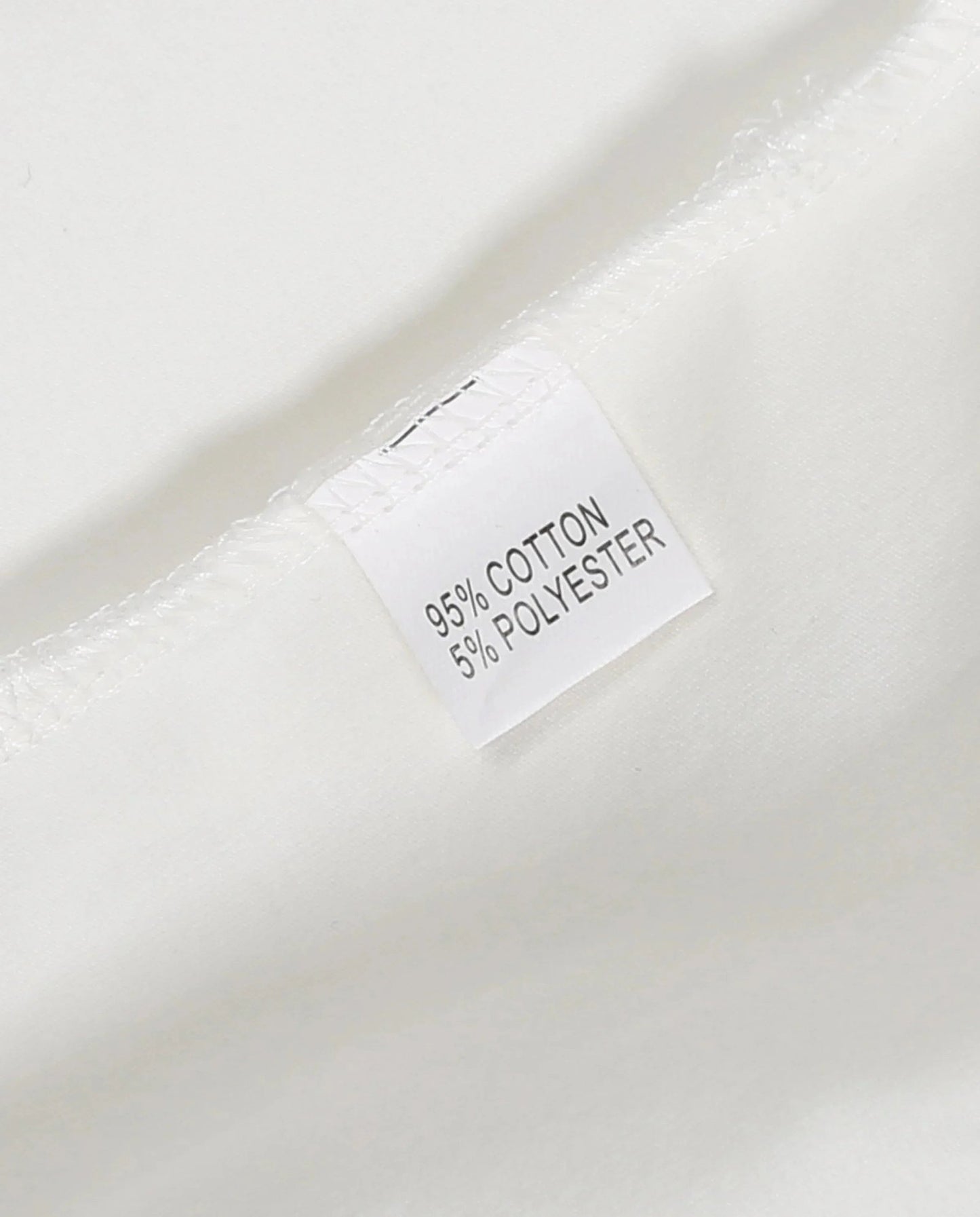 Care label on plaid romper baby clothes showing 95 percent cotton and 5 percent polyester composition