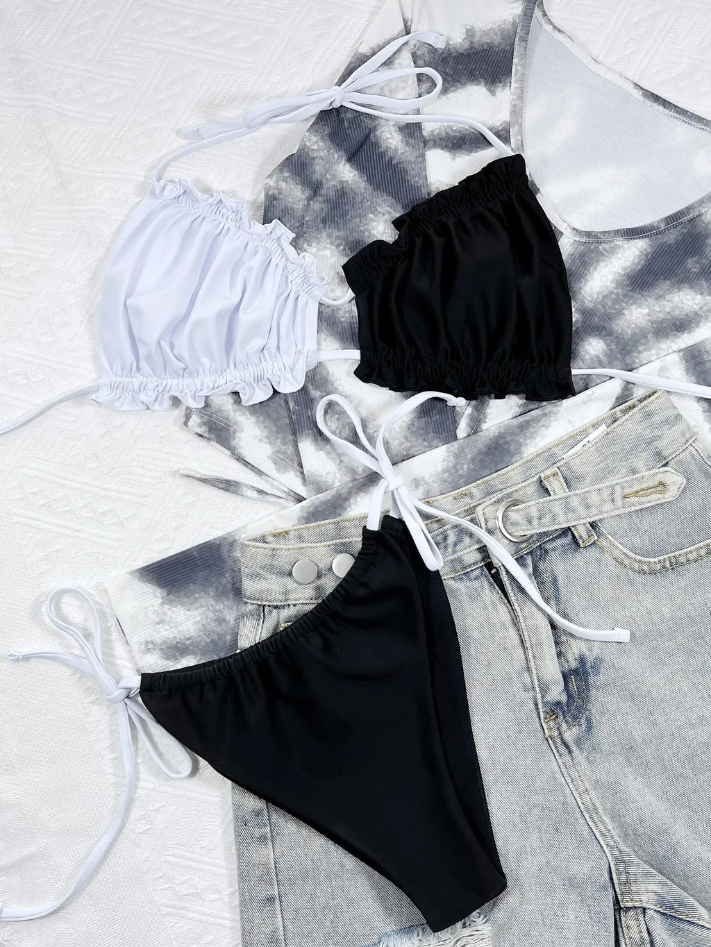Stylish beugel bikini set featuring a white top and black bottoms, paired with casual denim shorts