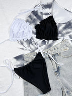 Stylish beugel bikini set featuring a white top and black bottoms, paired with casual denim shorts