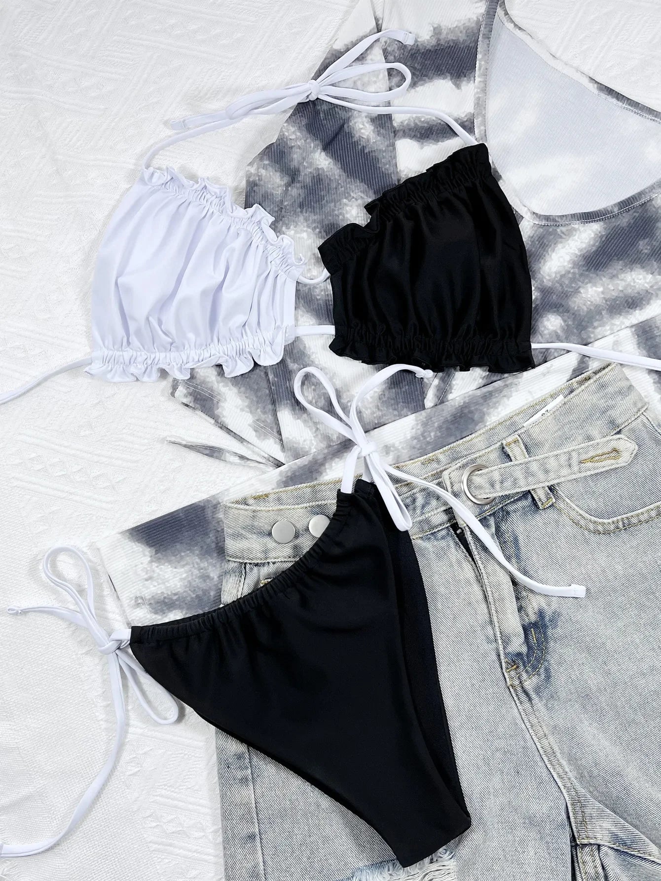 Stylish beugel bikini set featuring a white top and black bottoms, paired with casual denim shorts