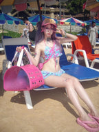 LuckeLadybug beugel bikini set with colorful floral patterns, worn at the beach with a pink accessory bag