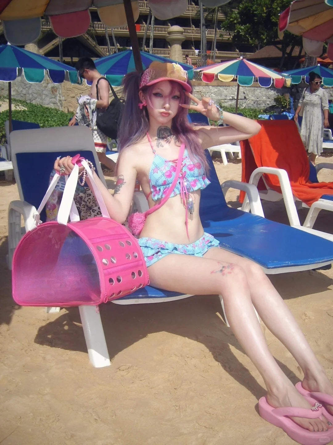 LuckeLadybug beugel bikini set with colorful floral patterns, worn at the beach with a pink accessory bag