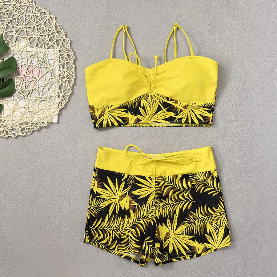 Bright yellow bikini with high waist featuring tropical leaf patterns for a stylish beach look