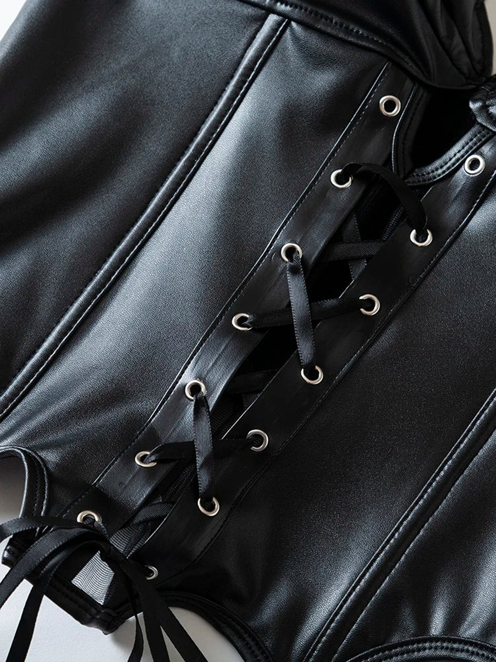Close-up of a black strapless corset top with lace-up detailing and shiny fabric finish