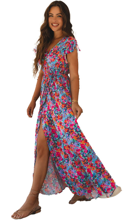 LuckeLadybug blue floral maxi dress on smiling model with v neck high slit flutter sleeves in boho living room