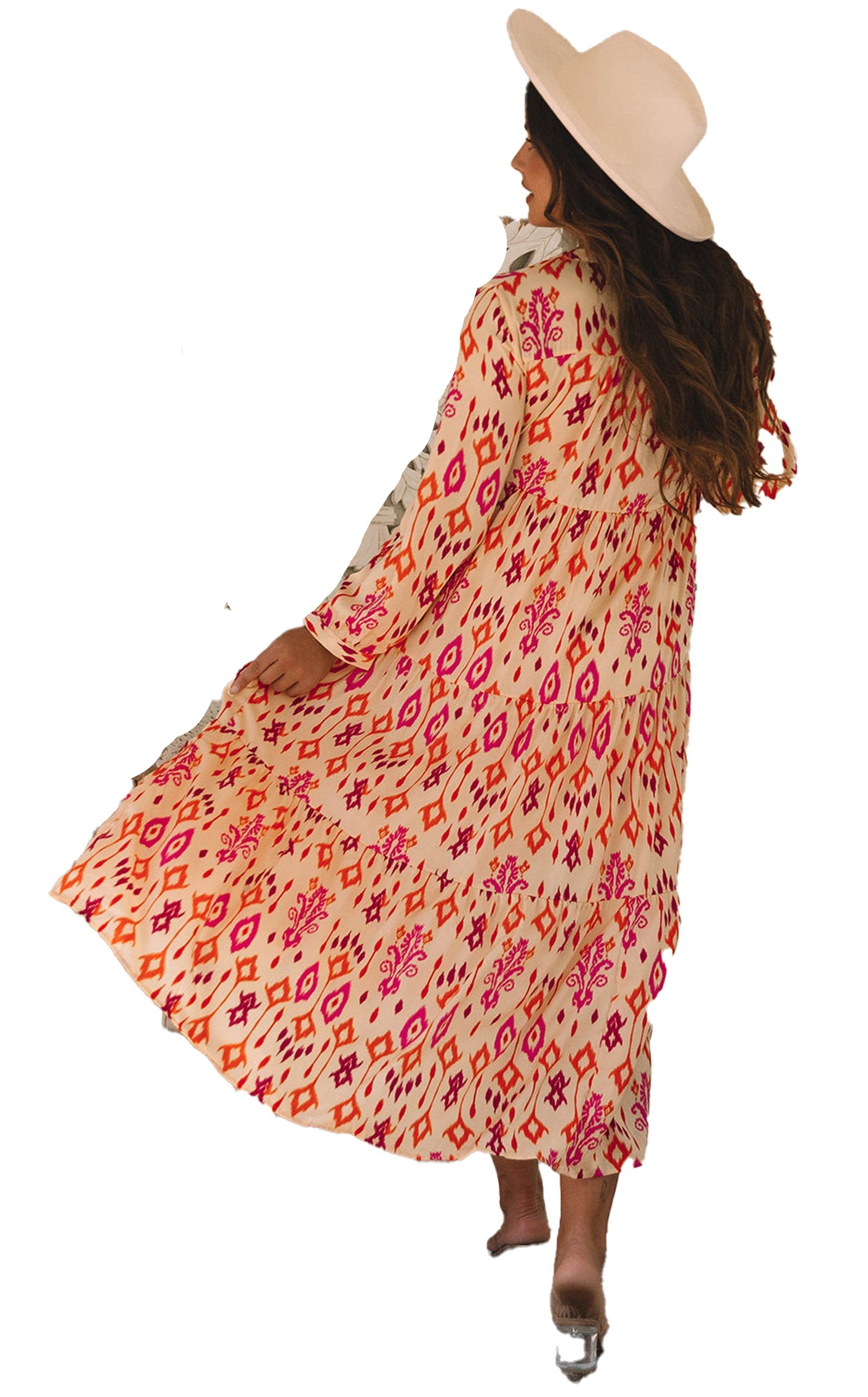 Woman twirling in an orange geometric maxi dress with boho hat and block heels in a cozy living room