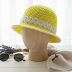 Handmade yellow bucket hat bucket with white floral trim displayed on a wooden mannequin head
