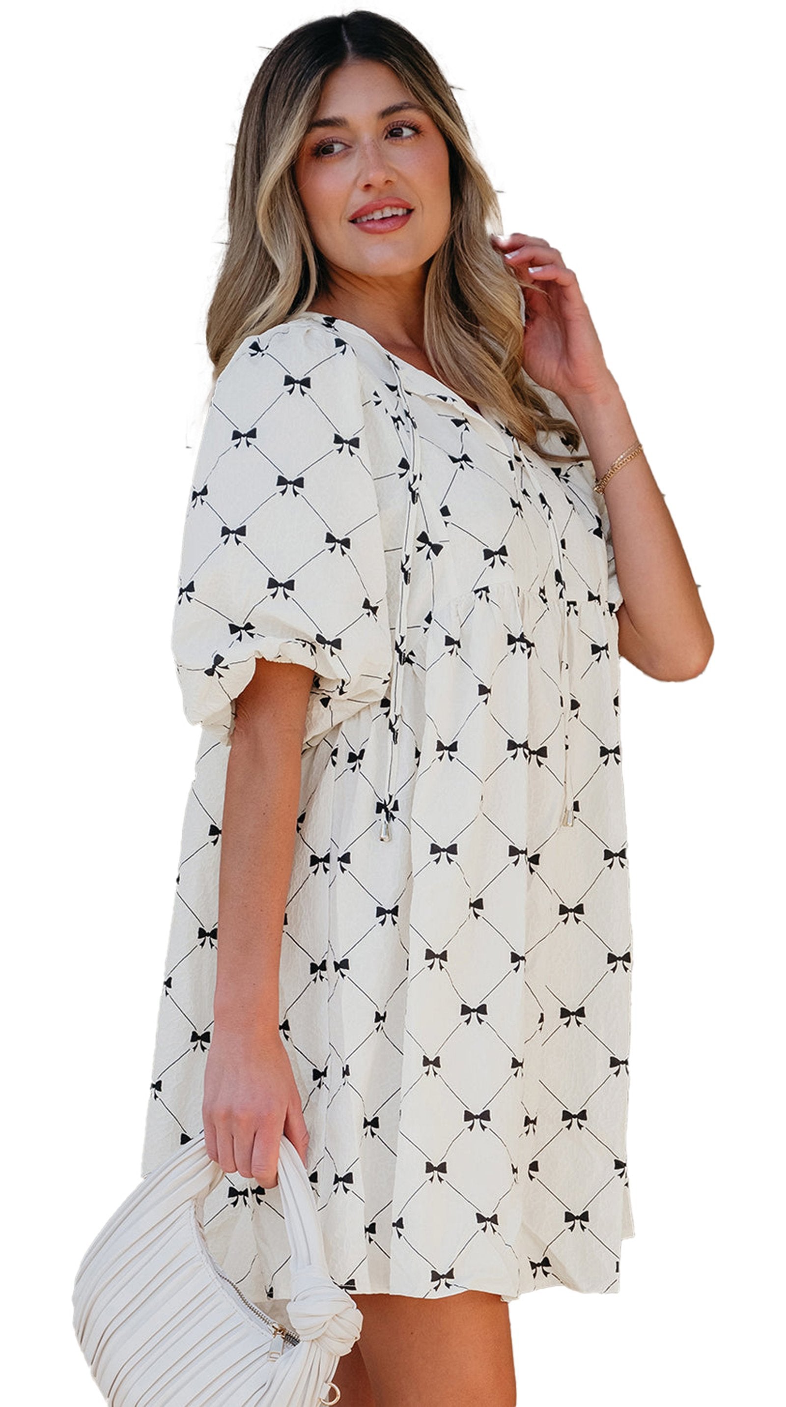 Model wearing Dear Lover Dropshipping white bowtie mini dress with puff sleeves and A line silhouette holding a white handbag