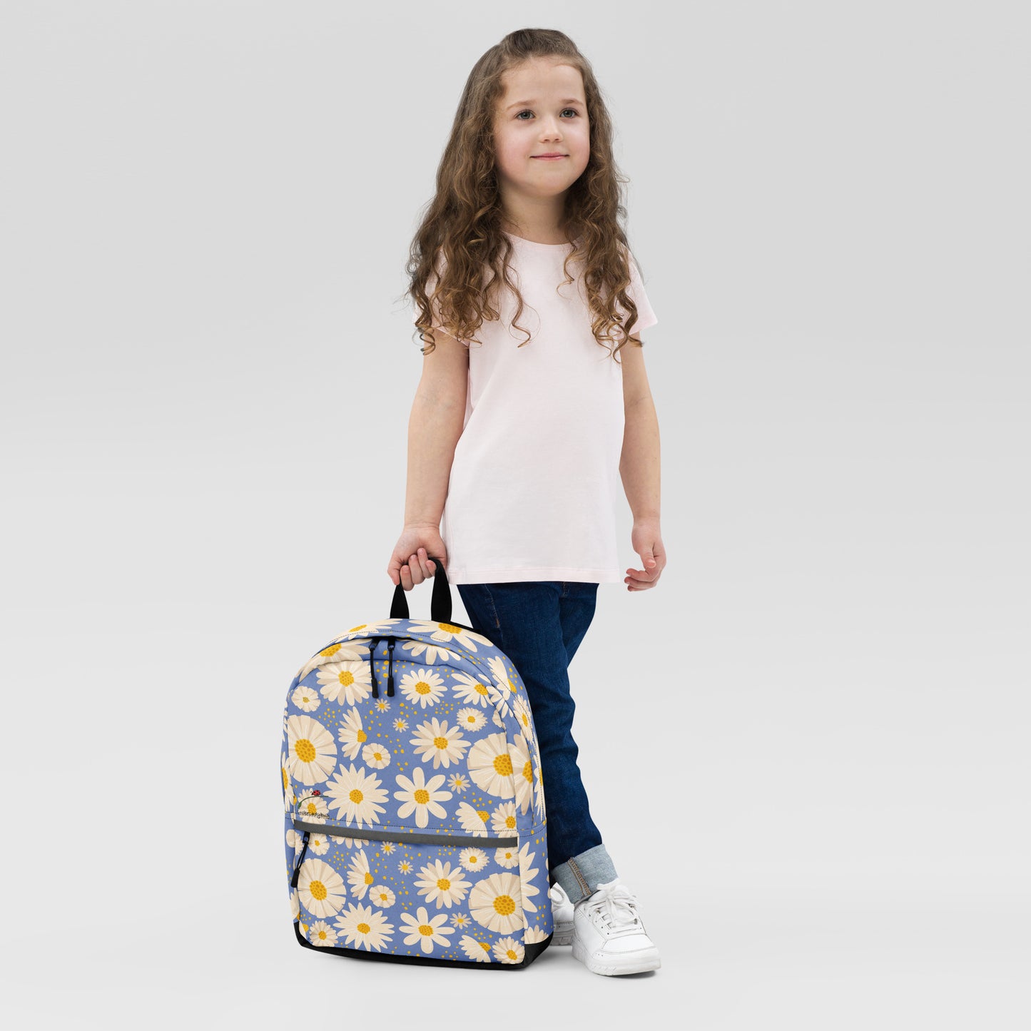 Girl holding trendy flower backpack with yellow and white daisy pattern and black accents