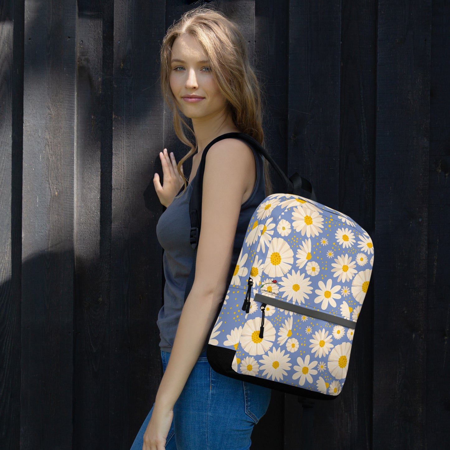 Woman wearing trendy flower backpack with white and yellow daisies on blue background