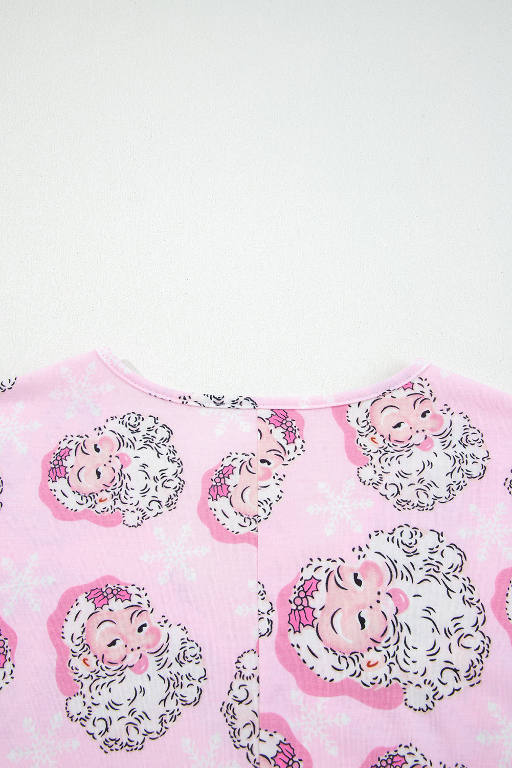 Pink Christmas pajamas featuring Santa Claus faces and snowflake patterns for festive wear