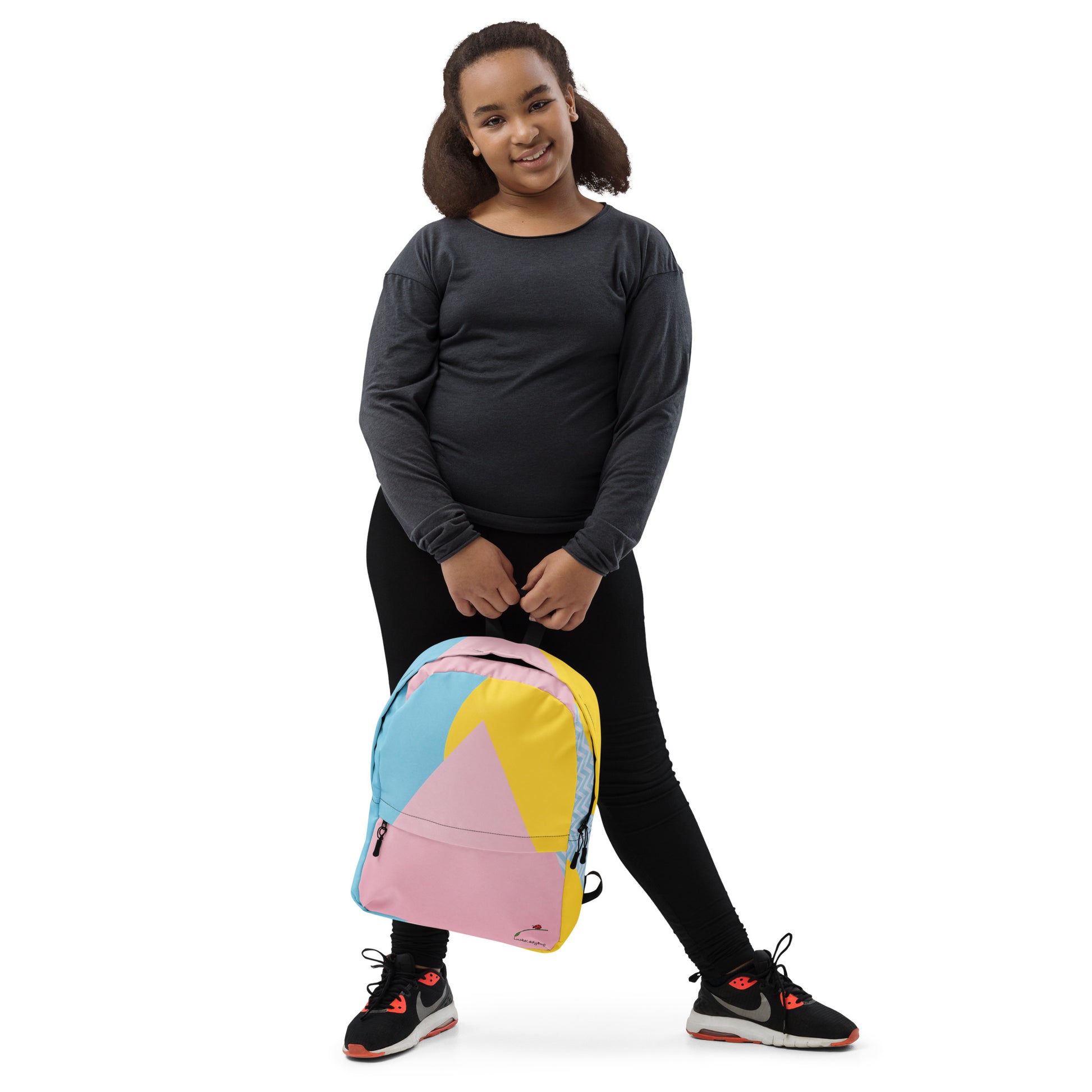 Young girl holding a colorful trendy backpack with pastel pink, blue, and yellow geometric design