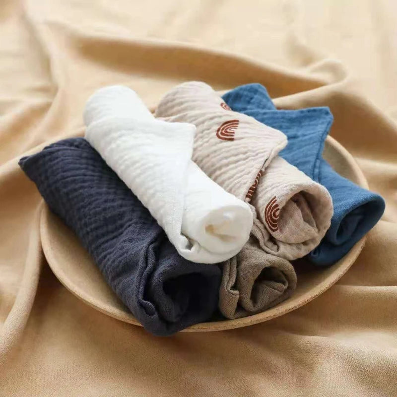 Set of soft cotton washcloths in various colors folded neatly on a plate