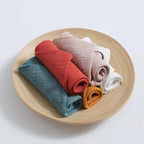 Set of soft cotton washcloths in various colors displayed in a wooden bowl