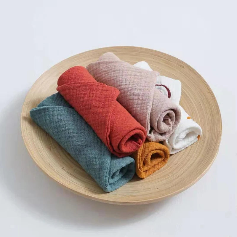 Set of soft cotton washcloths in various colors displayed in a wooden bowl