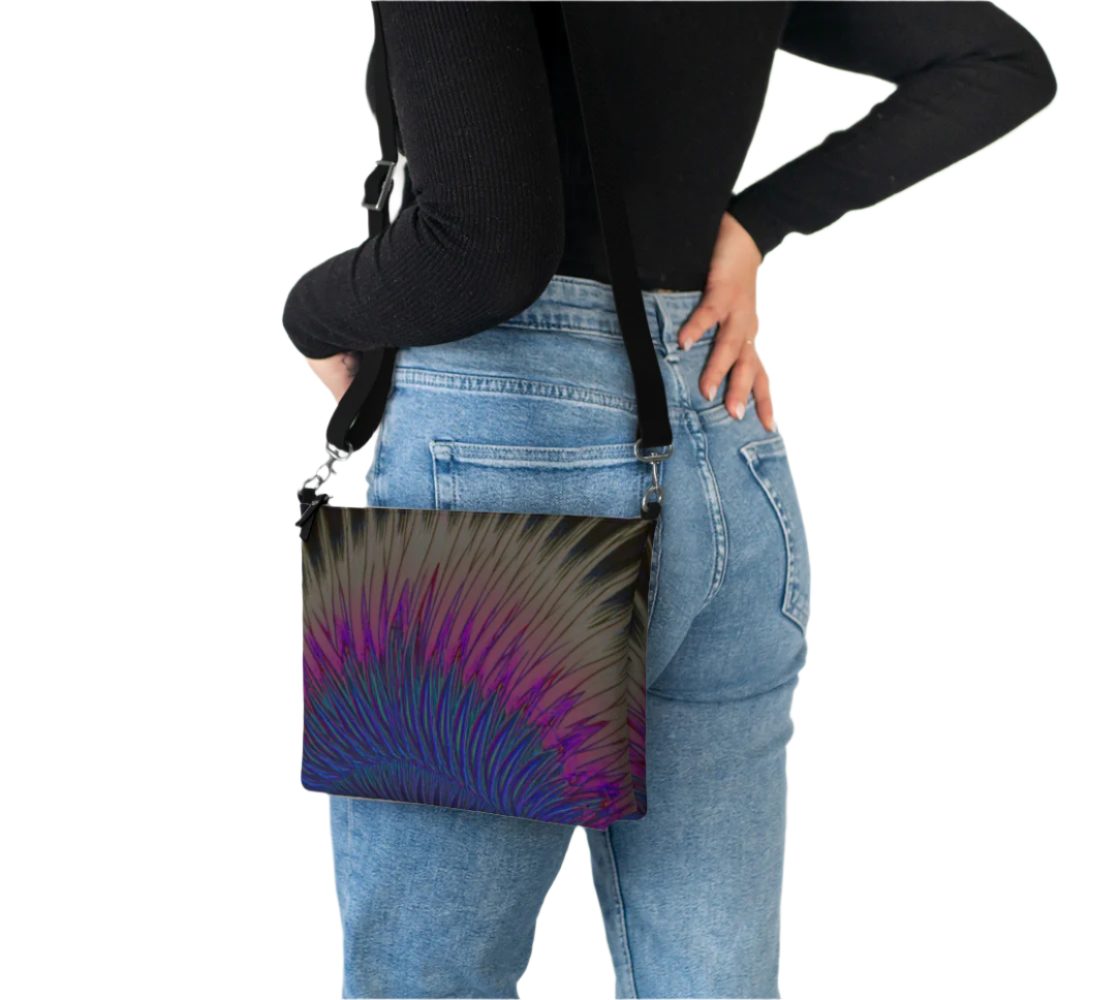 Vegan leather punk crossbody bag with vibrant feather design worn by person in black top and blue jeans
